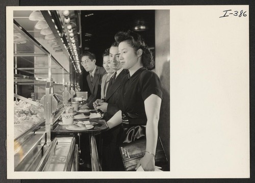 Shown with their trays at the salad counter in one of New York City's famous Automat restaurants just off Fifth Avenue are Barbara Yamamoto, Gila; Akira Kashiki, Colorado River; May Tomio, Granada; and Sam Kai, Tule Lake and Jerome. Photographer: Iwasaki, Hikaru New York, New York