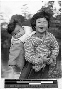 Smiling girl carrying a child on her back, Japan, 1936