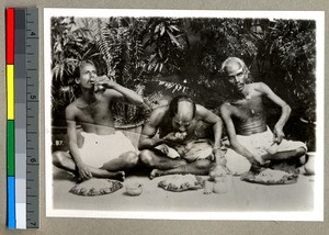 Three men eating on the ground without utensils, Vārānasi , India, ca. 1920
