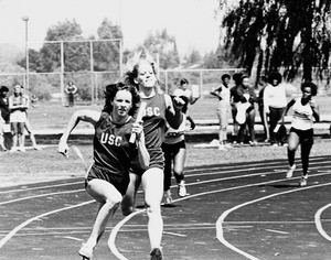 Lindsay Cassidy with baton and Sandy Crabtree of USC running in a relay race, 1979