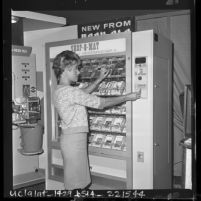 Louise Peden demonstrates coin operated vending machine at Automatic Merchandising show in Los Angeles, Calif., 1963
