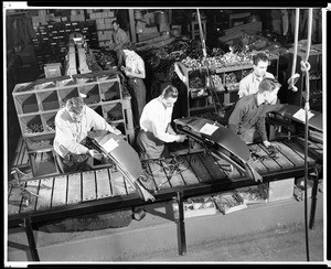 Workers assembling dashboards for automobiles in an unidentified factory