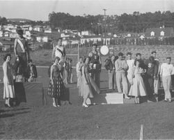 Analy High School Track medal awards ceremony 1951--four girls in dresses with corsages stand in front of the athletes standing on platforms