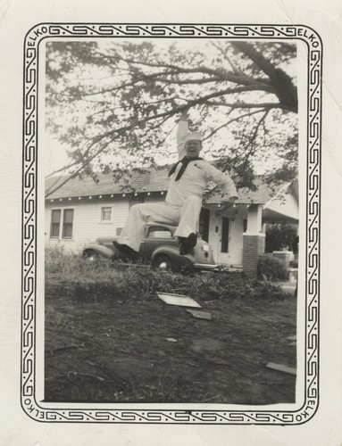 Lloyd Holmes in uniform swinging from tree