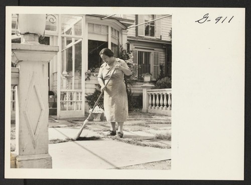 Mrs. Shigeko Sakamoto sweeps the terrace at the home of Mrs. H. D. Warner in Fairfield, Connecticut, where she and