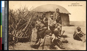 Indigenous men and women sitting near dried bushes, Lesotho, ca.1900-1930