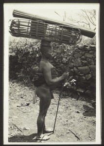 Bali woman en route for her farm, carrying her child on her back. When she returns in the evening the basket on her head will be full