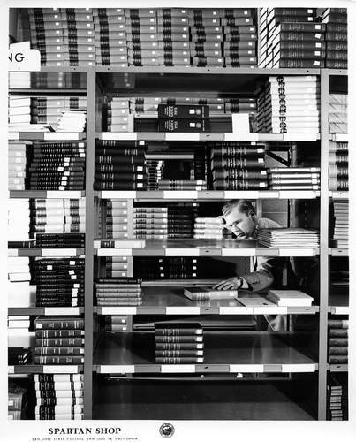 Student Stacking Textbooks at the San Jose State College Spartan Shop