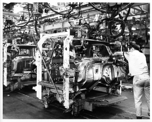 Worker Engaged in Manual Assembly of Automobiles at the Fremont GMC Plant