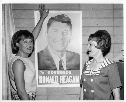 Two Women Posing with a Campain Poster of Ronald Reagan