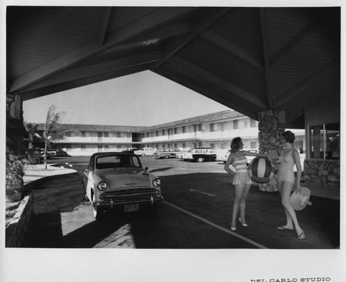 Two Women Next to a Parked Car at the Front Entrance of the San Jose MoteLodge