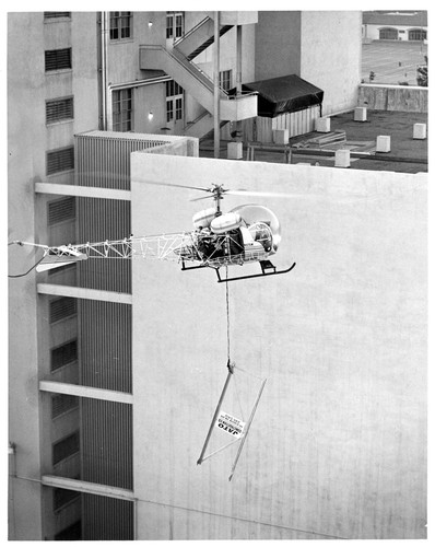 View of Helicopter Airlifting a Jato Construction Sign to the Top of a Building