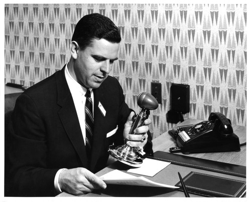 Gentleman Reading an Announcement over the Emporium Store Intercom