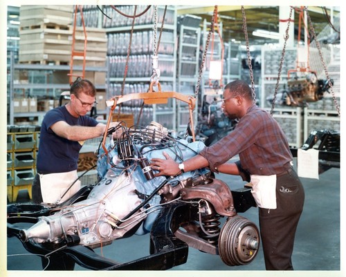 Two Workers Handling an Engine Block at the General Motors Corp. Assembly Plant