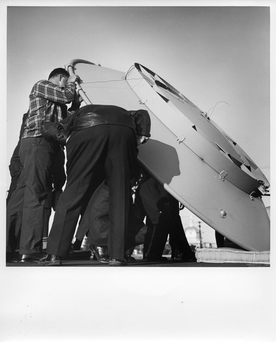 Image of Several Men Lifting Up a Large Telephone Company Rooftop Satellite Dish