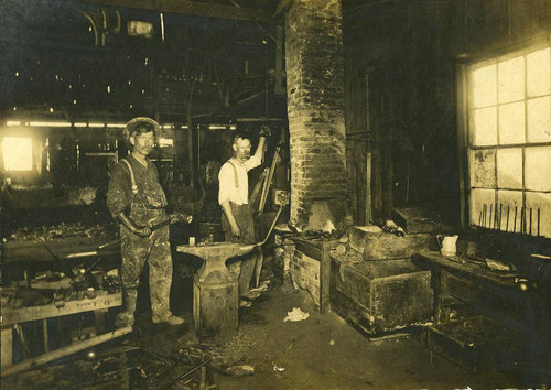 Walter Harper with his cousin Henry Seeman in blacksmith shop, ca. 1916