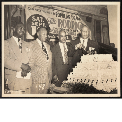 A. Philip Randolph cutting cake next to B.F McLaurin, Charles Burton, and Ashley Totten at the Silver Jubilee and 7th Biennial Convention of the Brotherhood of Sleeping Car Porters