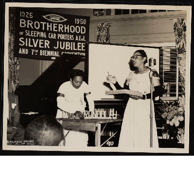 Woman speaking while woman arranges the letters Randolph on table at the Silver Jubilee and 7th Biennial Convention of the Brotherhood of Sleeping Car Porters