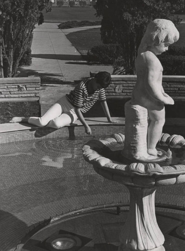 Student relaxes at fountain's edge on Pepperdine College campus, circa 1968