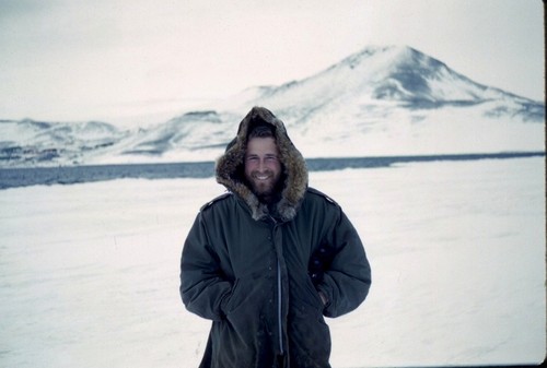 Paul K. Dayton, with McMurdo Station in left background. Standing on McMurdo Sound, Antarctica, 1964