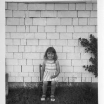 Young girl standing at the wall of a home