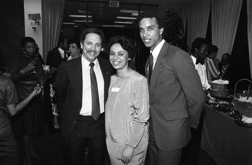 Karen E. Hudson posing with two unidentified men at the 98th birthday celebration of Dr. Claude H. Hudson, Los Angeles, 1984