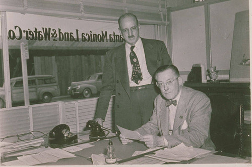 Mr. Lee (on the right) of Lee Insurance and associate in an office in the Santa Monica Land and Water Company building, Pacific Palisades, Calif