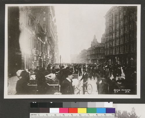 [Crowd gathered in Market St. to watch fire in distance. Looking northeast from near Geary, Kearny and Thirds Sts. Palace Hotel, right.]