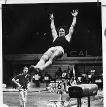 Chuck Gaylord of UC Davis drops with arms outstretched after leaping from the vault