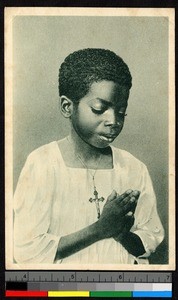 Young boy standing with hands clasped in prayer, Madagascar, ca.1920-1940