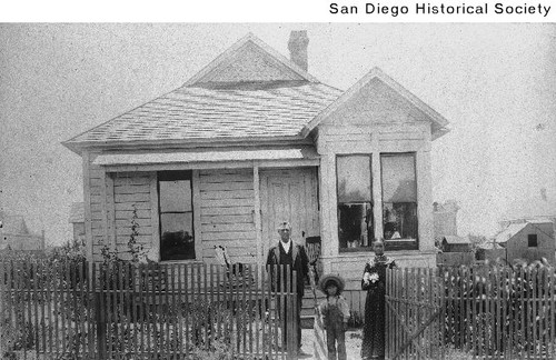 Amos and Cynthia Hudgins and their child standing outside their home in Coronado