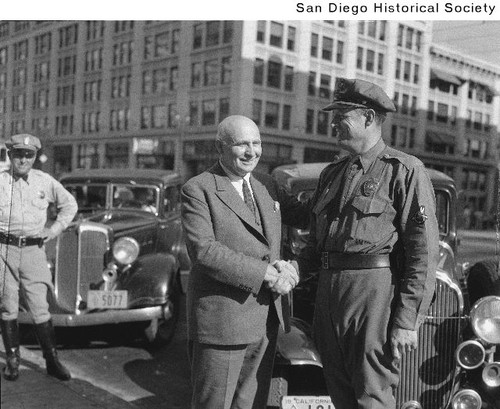 Acting Governor Frank Merriam shaking hands with a police officer on a downtown San Diego street