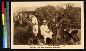 Seated missionary father surrounded by people, Benin, ca.1920-1940