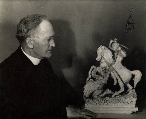 Father Scheoner next to a sculpture of St. George and a dragon