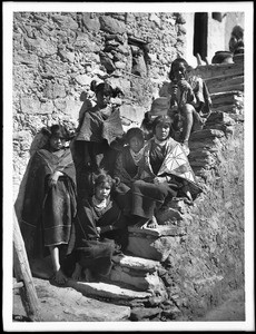 Five young Hopi Indian girls with an old Hopi Indian man sitting on stone steps in the village of Shonguapavi, ca.1901