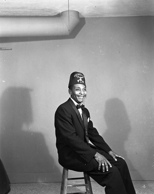 Portrait of man in bow tie and Menelik fez cap