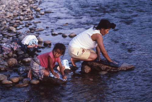 Guatemalan refugees wash clothes in a river, Ixcán, 1983