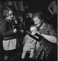 [Same scene as identified image: At Meyer's--Ammerschwihr(?): children being given medicine or cod liver oil by mother.]