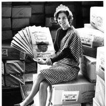 Queenly Display-Marion Whitehead, 1963 Camellia Festival Queen, poses with a million grocery bags announcing the upcoming 10th Annual Camellia Festival