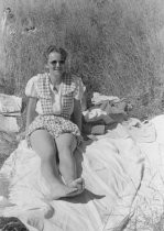 Woman sitting on blanket on the ground, unknown