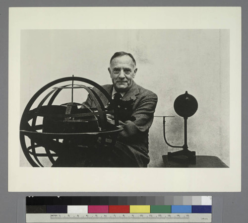 Edwin Powell Hubble, seated with his cat Nicolas Copernicus, behind an armillary sphere