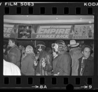 People in theatre lobby decorated with "Empire Strikes Back" banner in Los Angeles, Calif., 1980