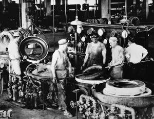 Workers removing a tire from a mold in a Los Angeles tire factory, ca.1930