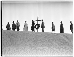 Nine people in a line in front of a cross at a funeral