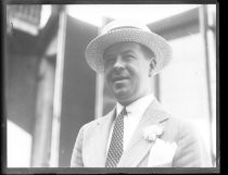 Man in suit, with polka-dot tie and straw boater hat