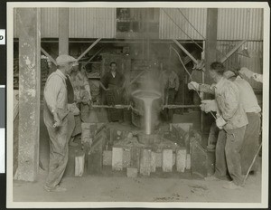 Workers pouring molten bronze into mold at an unidentified factory, ca. 1925