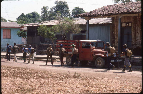 Guerrilleros walk in the street with their backpacks on, San Agustín, 1983