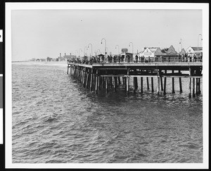People fishing off the side of an unidentified pier, 1930-1940