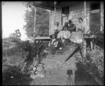 Family with dog seated on stairs of cabin