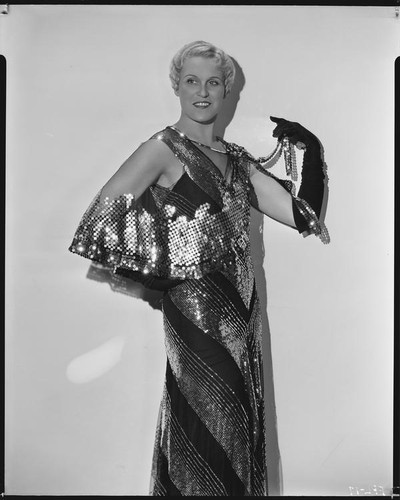 Peggy Hamilton modeling a Travis Banton gown of black net with gold palettes and sequins, 1931